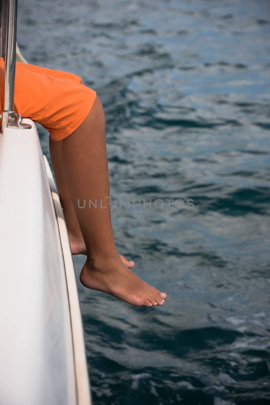 Young boy sitting on a yacht side. The journey across the ocean