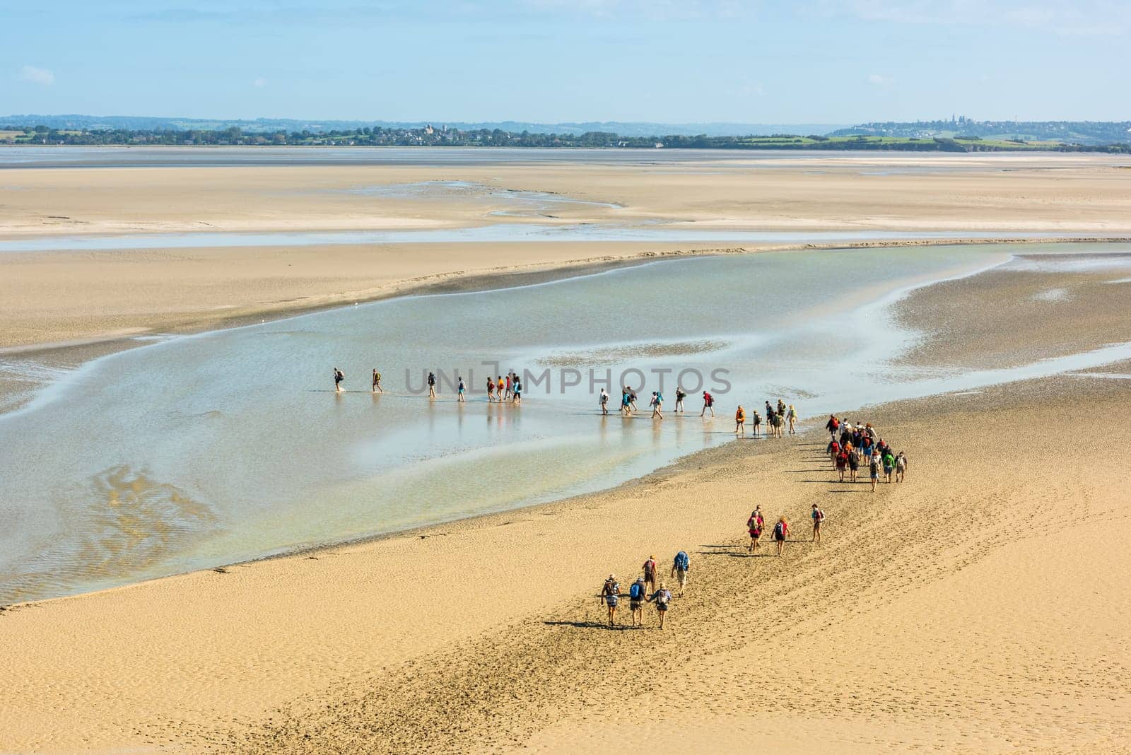 FRANCE, MONT SAINT MICHEL - SEPTEMBER 26: View from walls of Mont Saint Michel on the bay during the low tide with groups of tourists walking. France on September 26, 2015