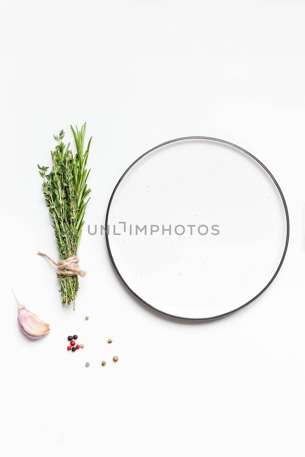 Flat lay overhead view empty plate mockup blank text space invitation card on white background with greens herbs and spices. Menu design food background with cooking ingredients