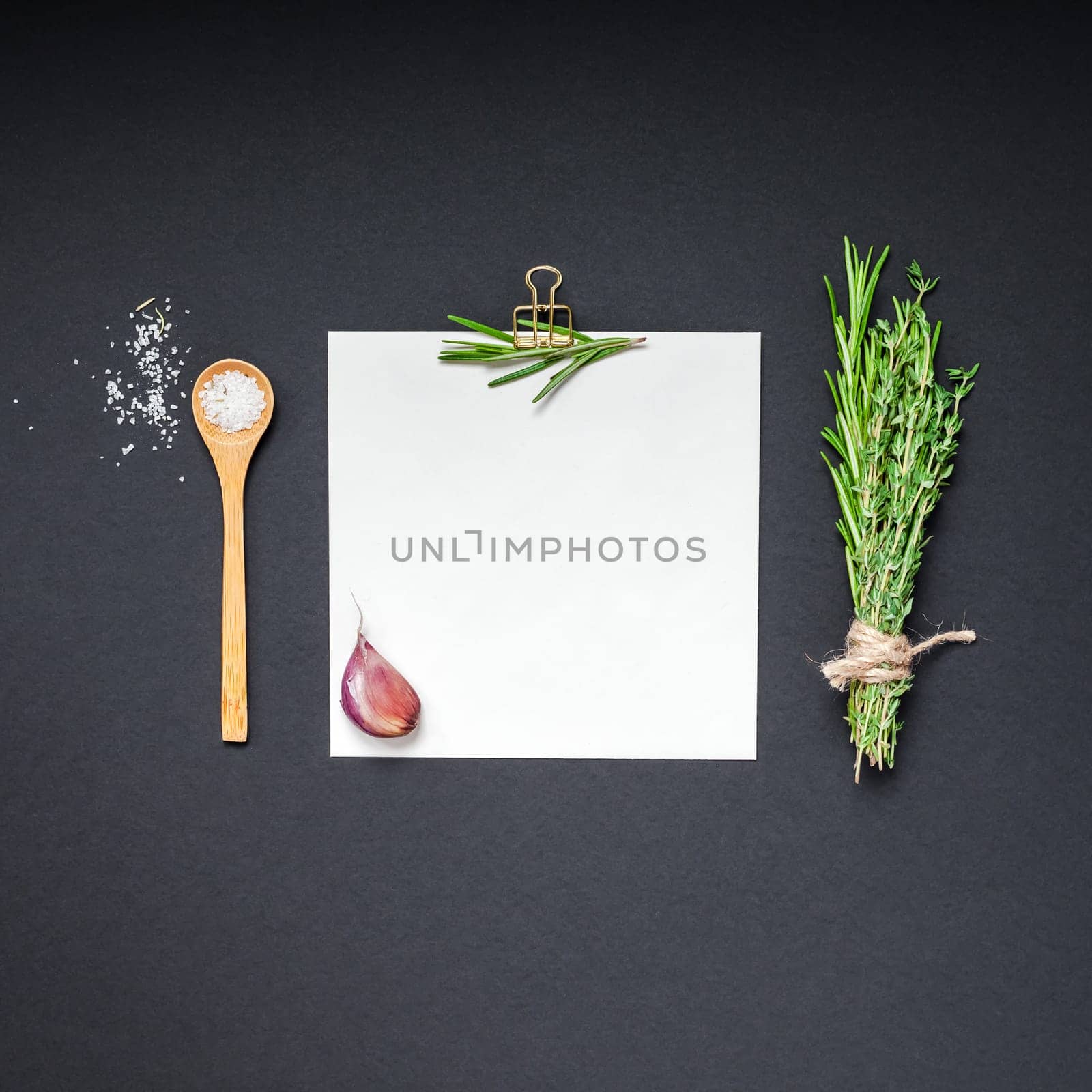 Flat lay overhead view blank recipe paper page with clip mockup text space invitation card on black background with greens herbs and spices. Menu recipe book food blog design with cooking ingredients