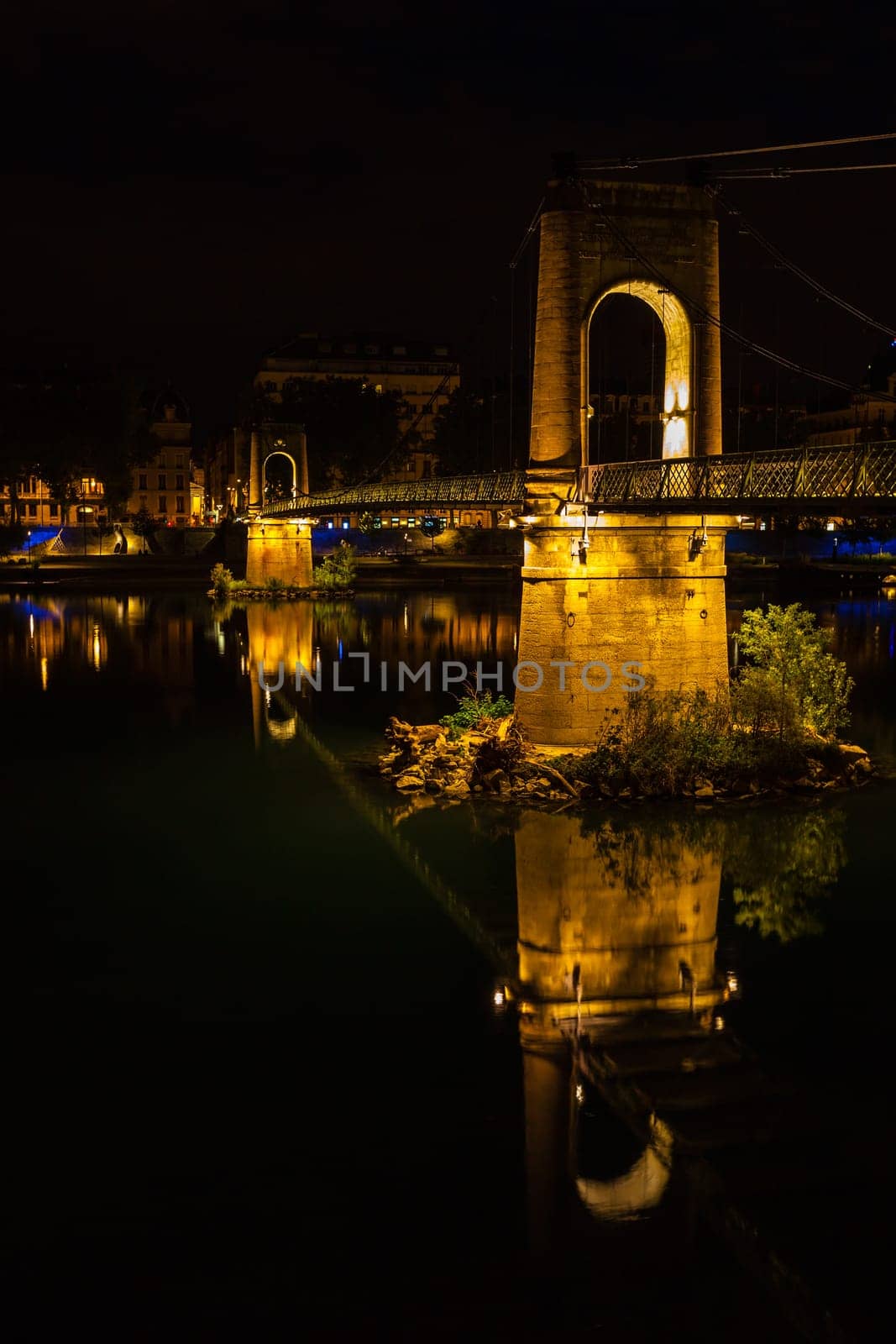 Old Passerelle du College bridge over Rhone river in Lyon, France at night