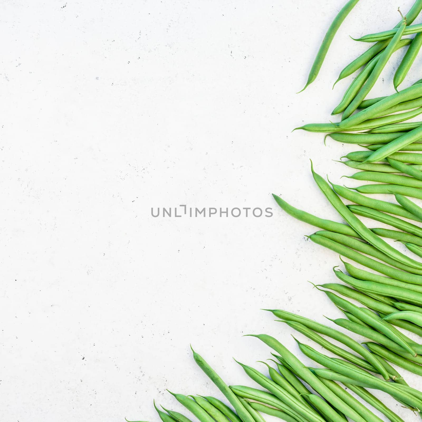 Creative scandinavian style flat lay top view of fresh green beans on white concrete table background copy space. Minimal house cooking concept template for blog or recipe book