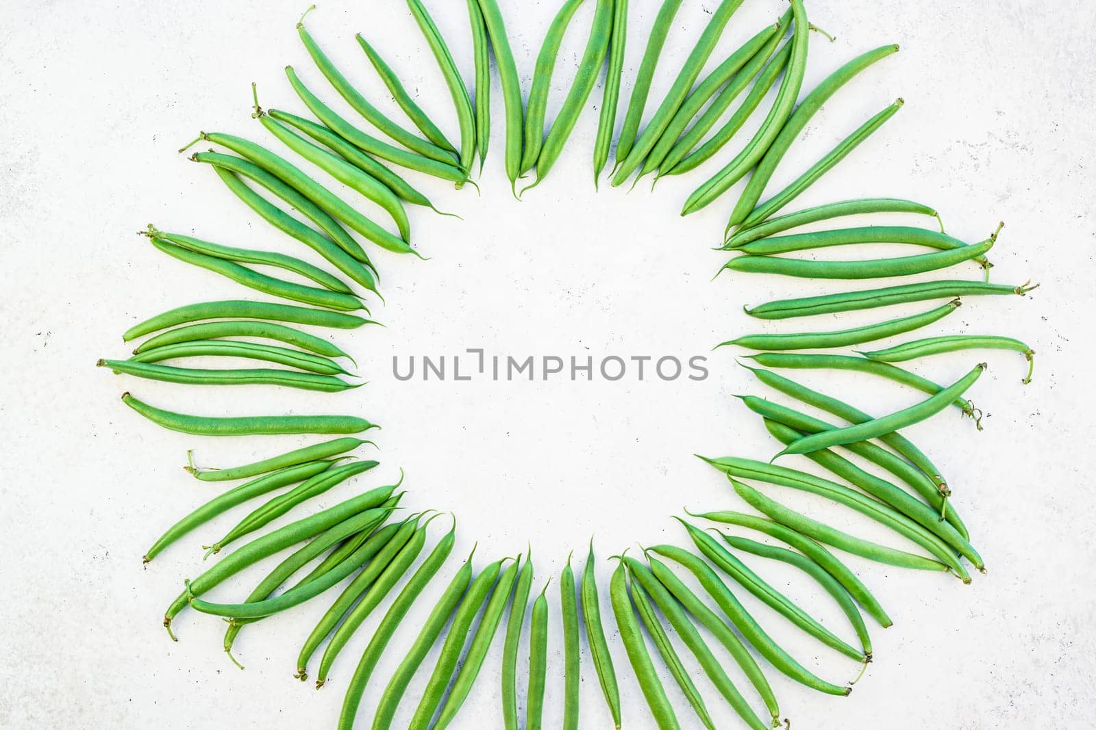 Creative scandinavian style flat lay top view of fresh green beans on white concrete table background copy space. Minimal house cooking concept template for blog or recipe book