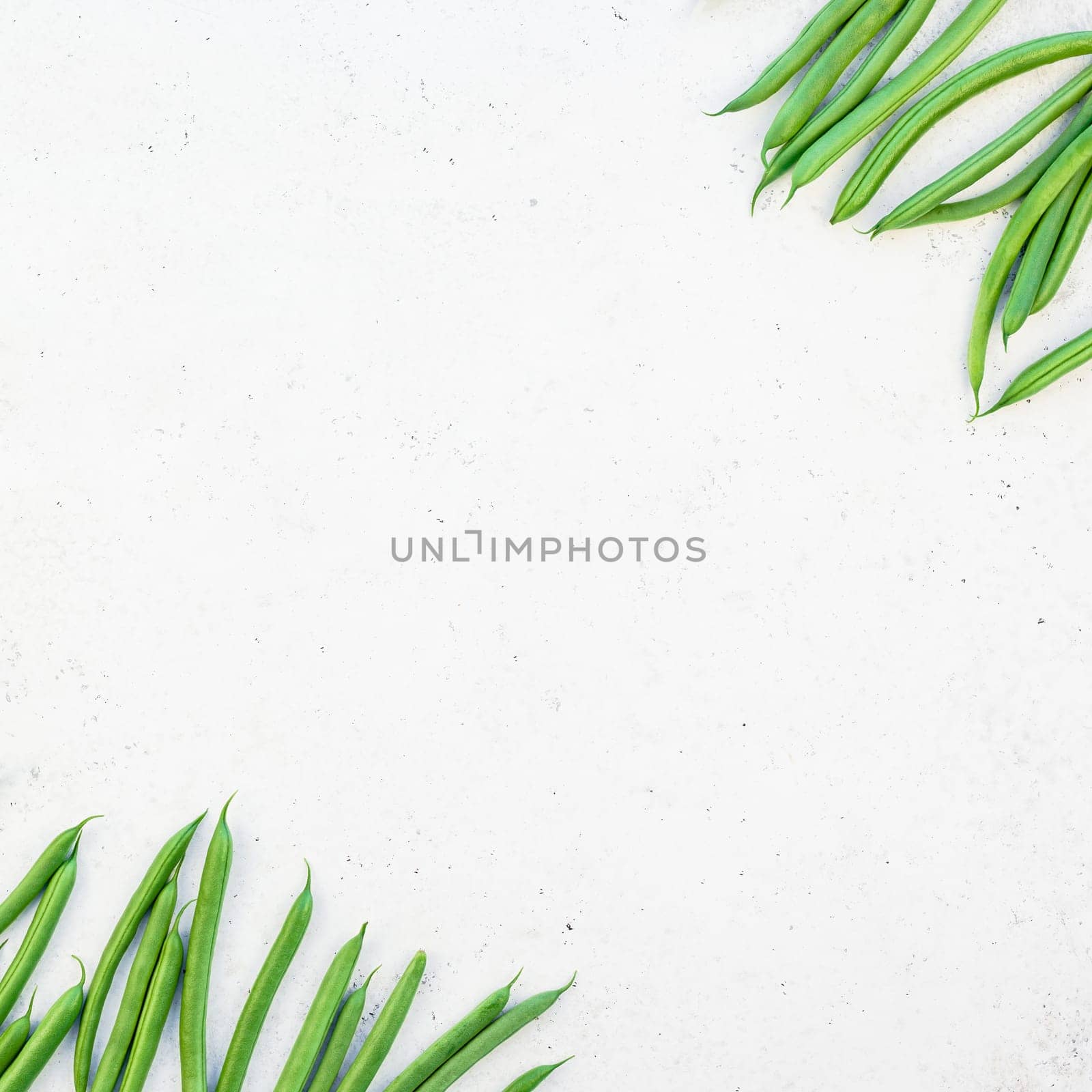Creative scandinavian style flat lay top view of fresh green beans on white concrete table background copy space. Minimal house cooking concept template for blog or recipe book