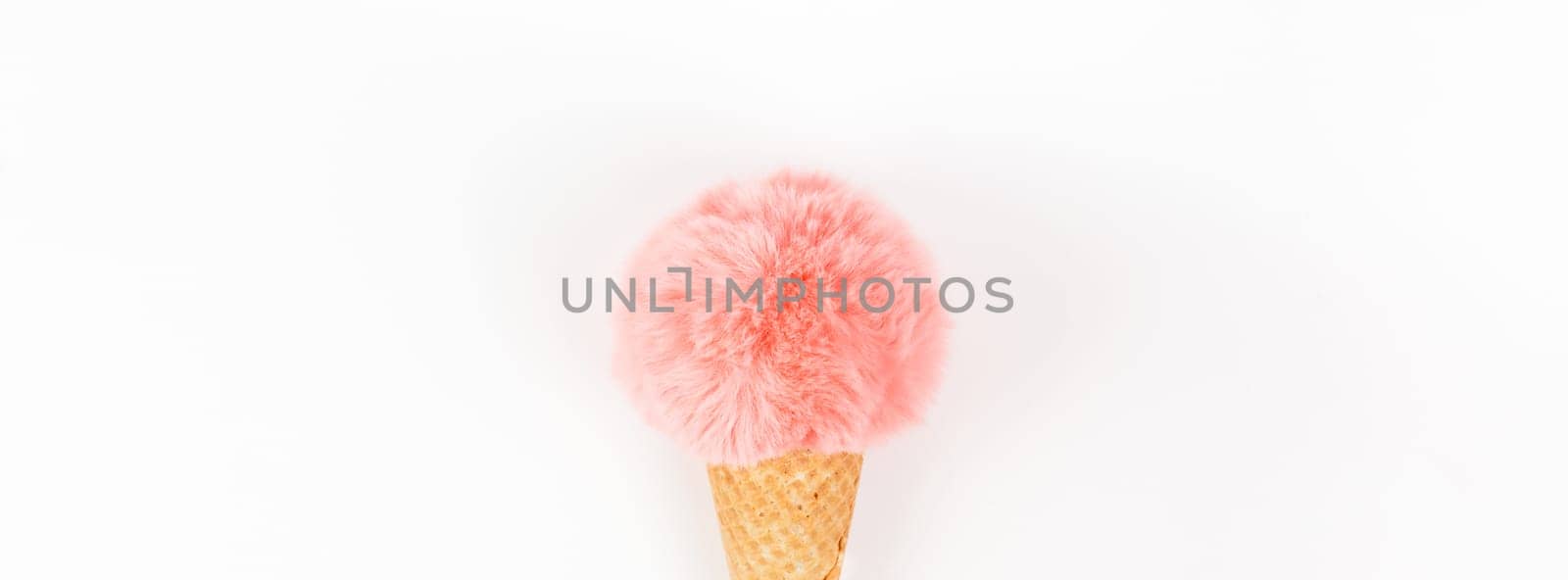 Creative top view flat lay of coral color fluffy fur ball in ice cream waffle cone with copy space on white background in minimal style. Concept feminine blog social media. Natural light with shadows
