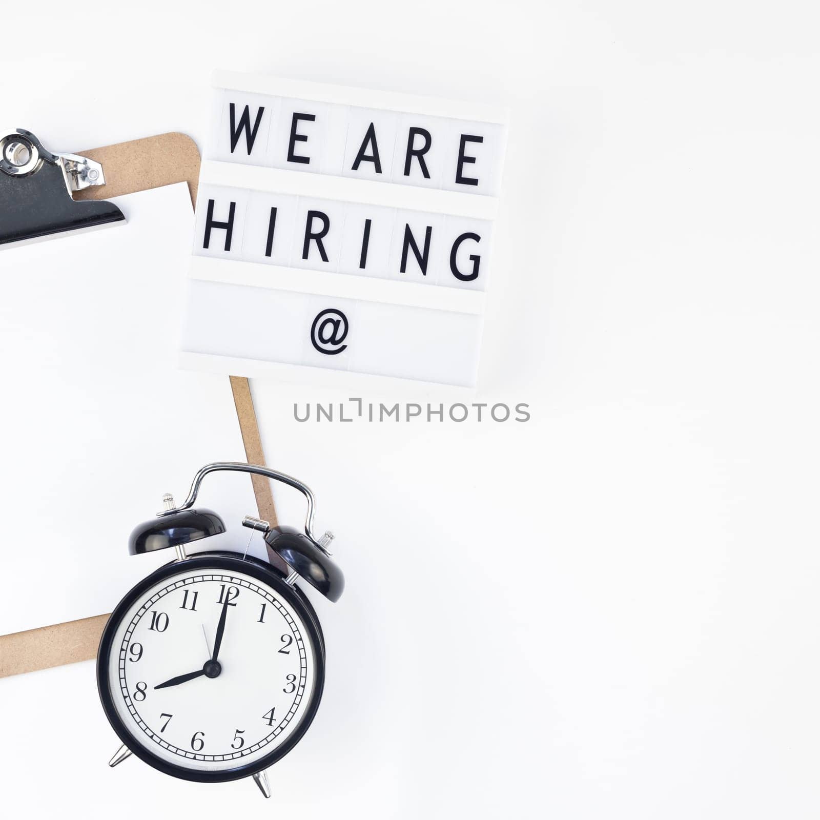 Creative top view flat lay of desk with we are hiring text on lightbox with copy space on white background in minimal style. Concept of new job, hiring recruitment process, new team members screening