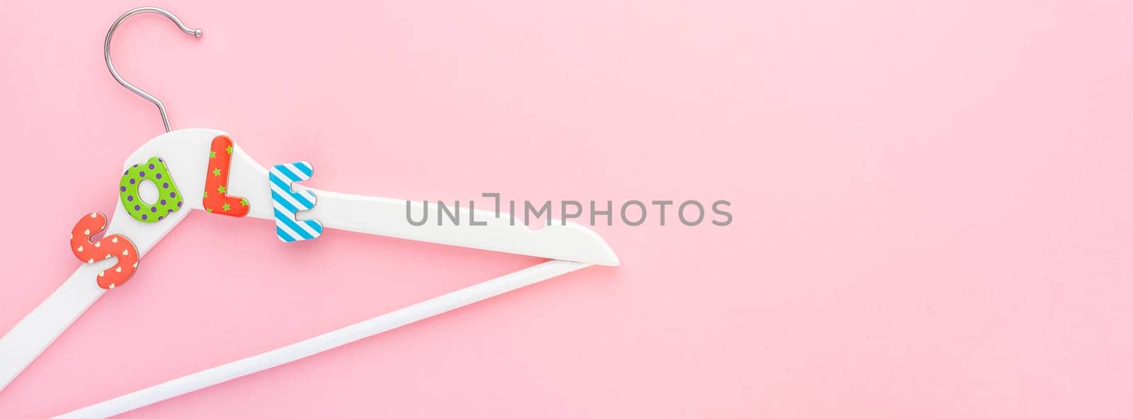 Creative top view flat lay white wooden hangers sale text pastel pink background copy space minimalism style. Template fashion feminine social media sale children store promo design shopping banner