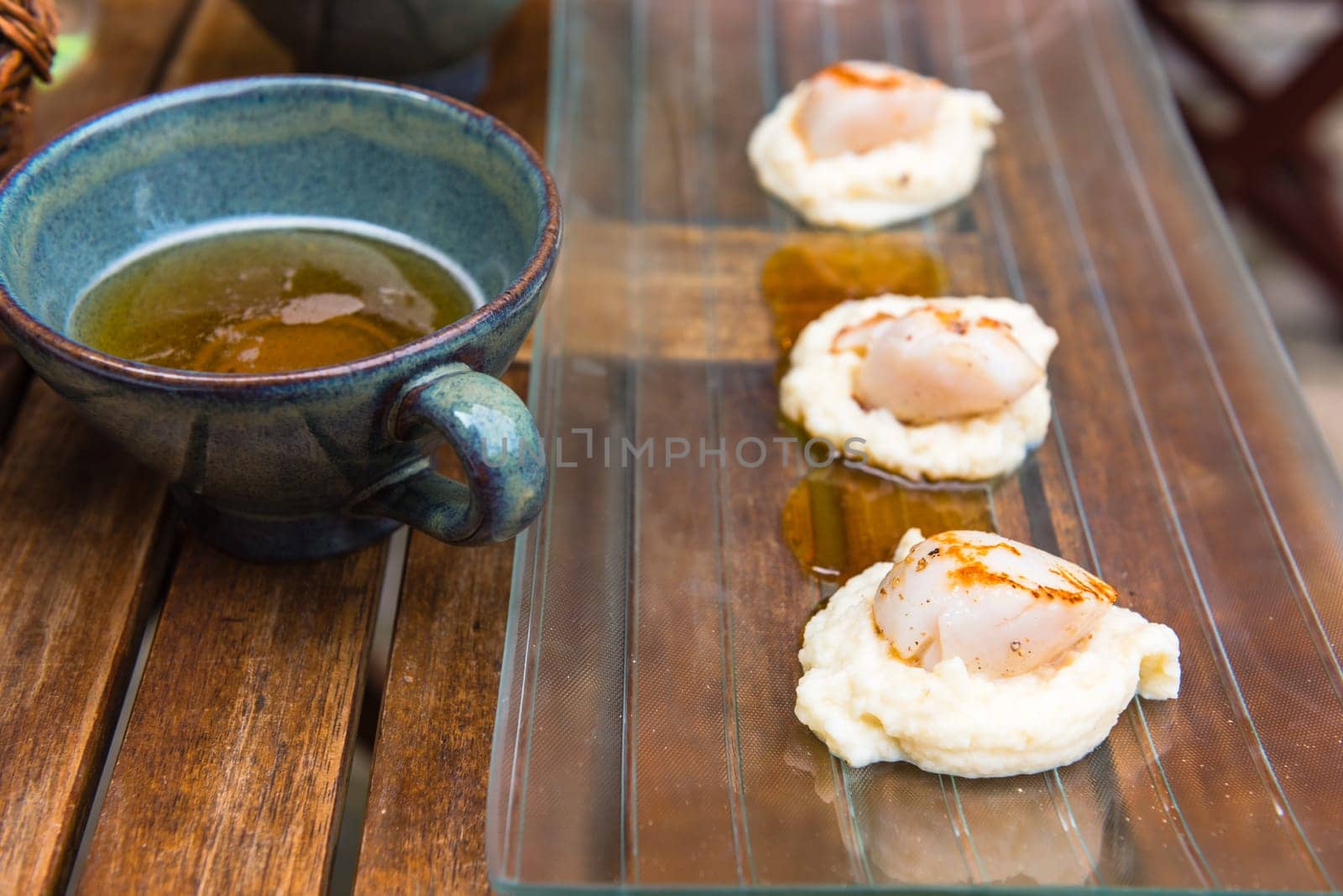 Close up of pan seared sea scallops and a cup of cider. Shot with a selective focus