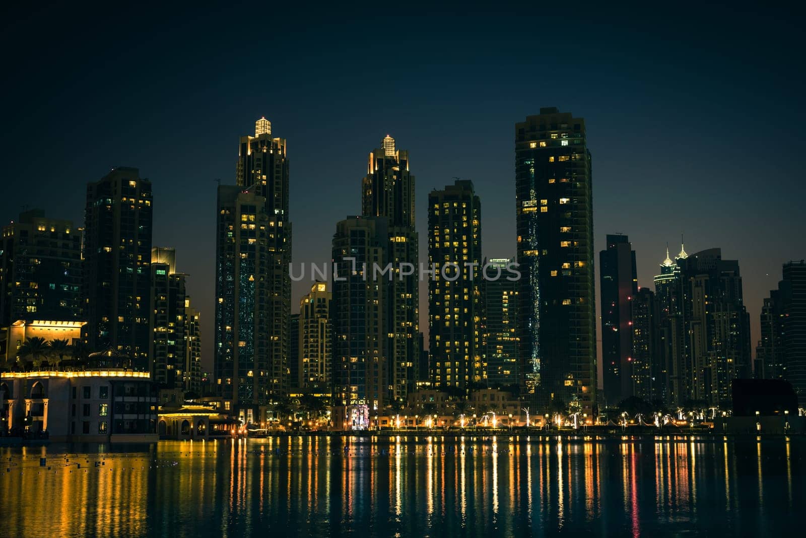 Night cityscape of Dubai city, United Arab Emirates. Reflections in the water. Filtered shot
