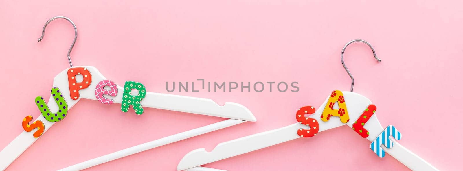 Creative top view flat lay white wooden hangers super sale text pastel pink background copy space minimalism style. Template fashion feminine blog social media sale store promo design shopping concept