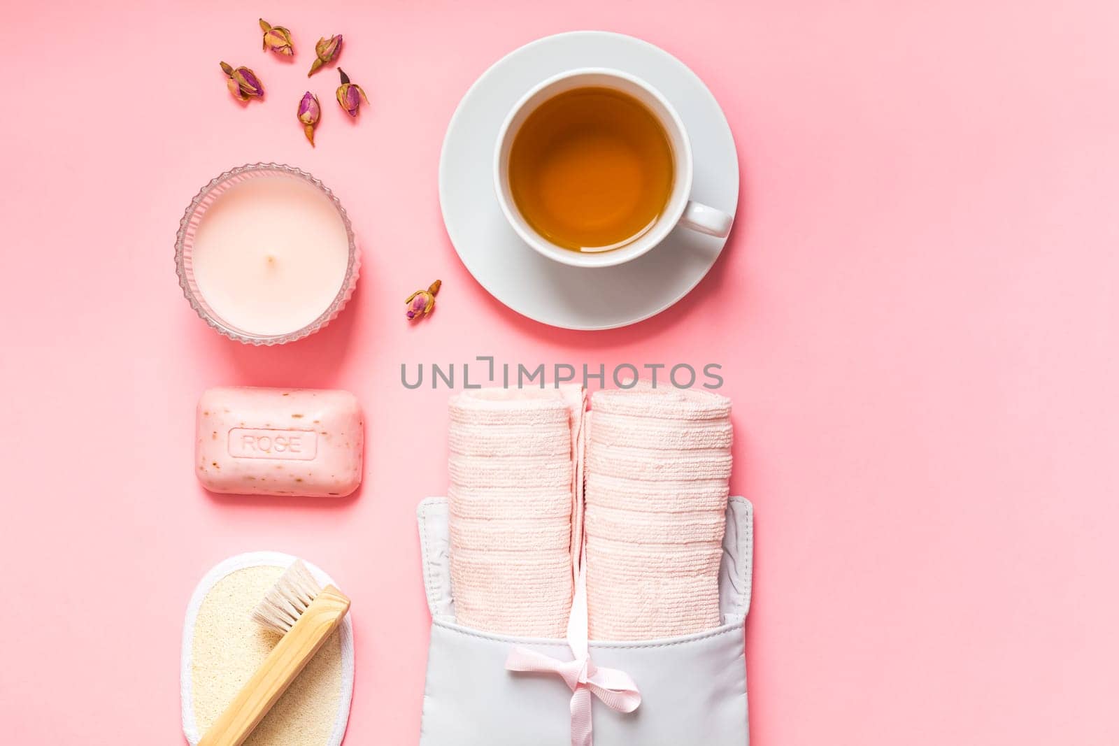 Spa, beauty cosmetics and body care treatment concept copy space. Creative top view flat lay composition bath accessories, rose organic cleansing soap, candle, cup of tea on pink background