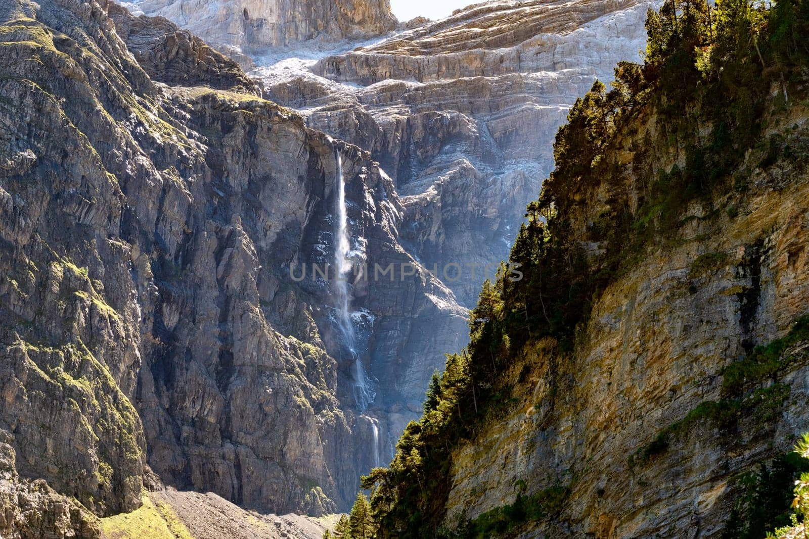 A mountain with a waterfall in the foreground. The waterfall is small and the mountain is very tall, Cirque de Gavarnie, France