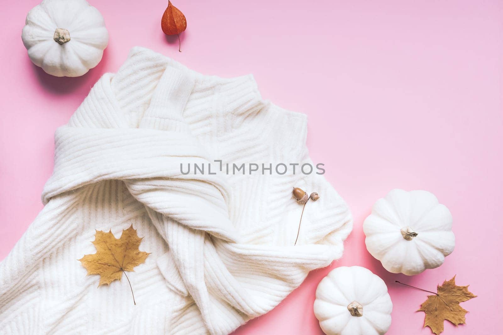 Creative autumn flat lay overhead top view white sweater and pumpkins on millennial pink background copy space minimal style with natural light. Fall season template for feminine blog social media