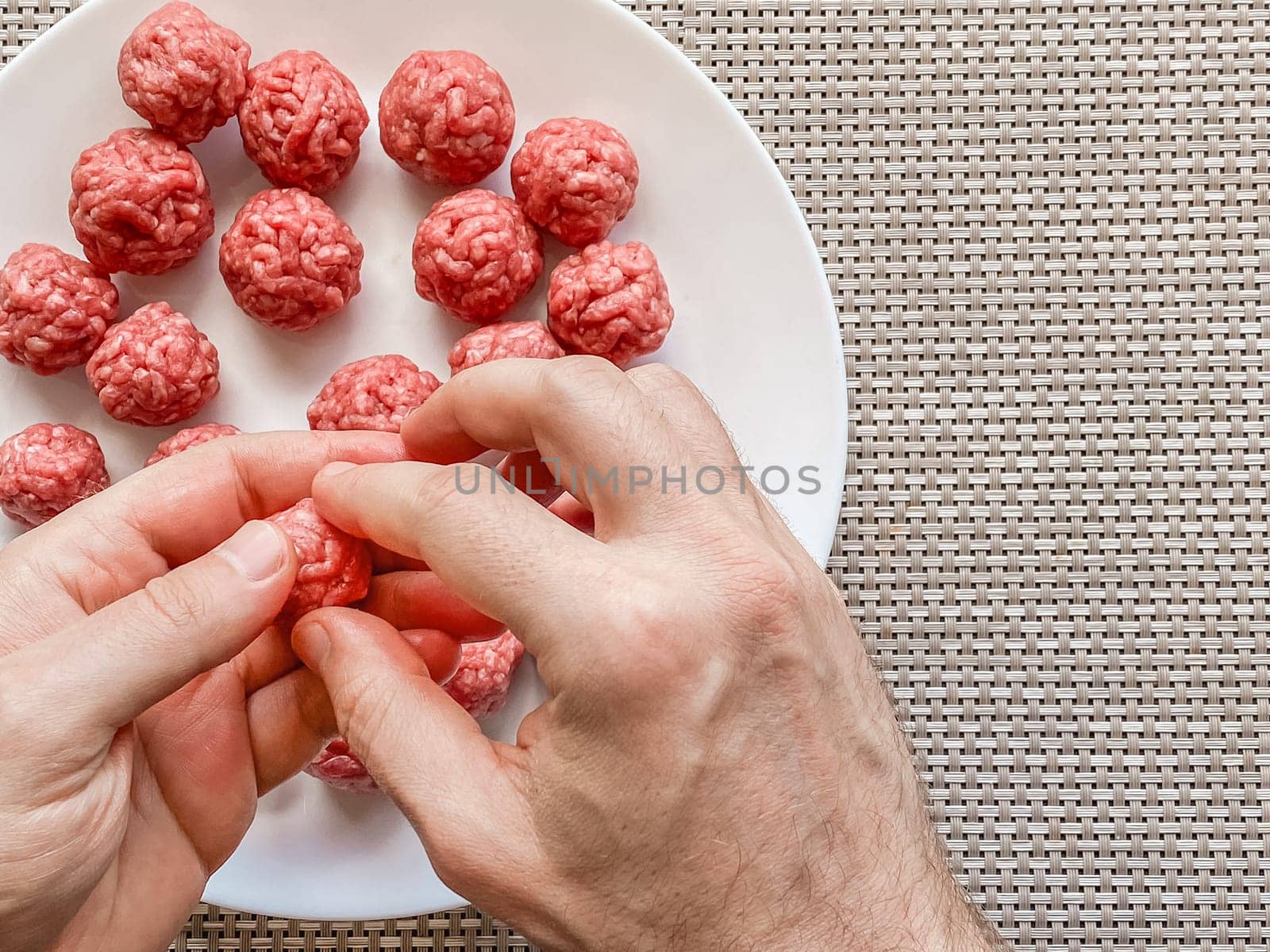 Man hands preparing meatballs with raw mincemeat. Lifestyle close up composition with natural light. Homemade cooking during lockdown, stay home housekeeping sharing concept. Top view with copy space