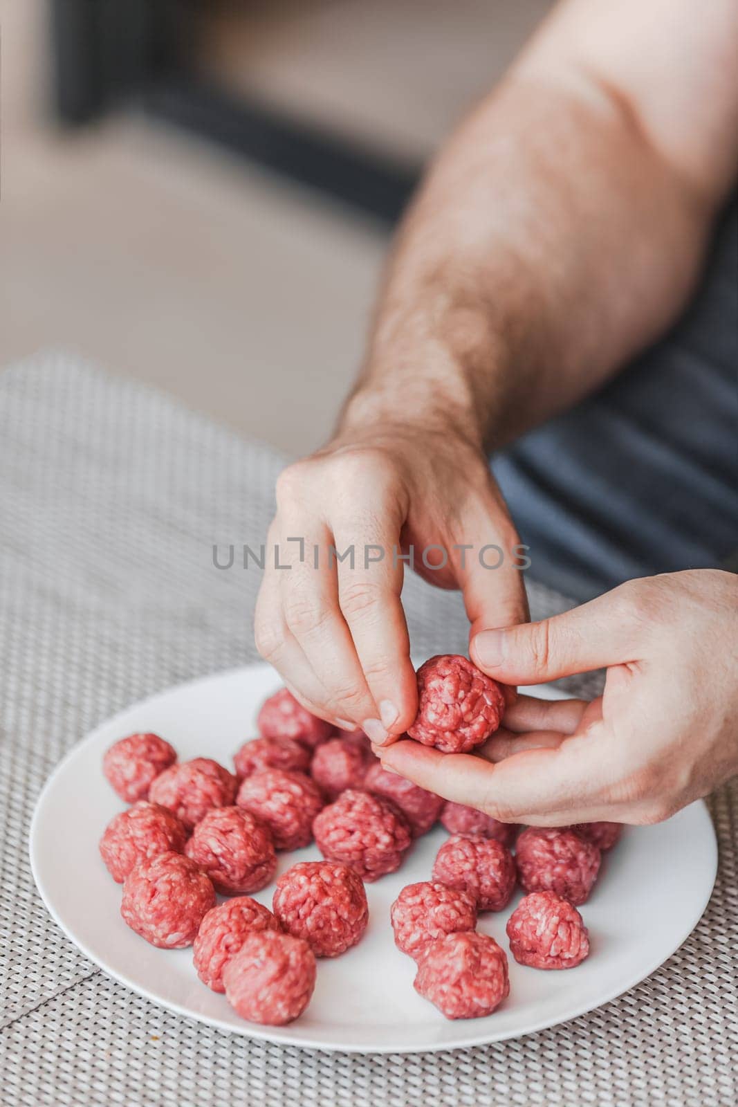 Man hands preparing meatballs with raw mincemeat. Lifestyle close up composition with natural light. Homemade cooking during lockdown, stay home housekeeping sharing concept. Side view with copy space