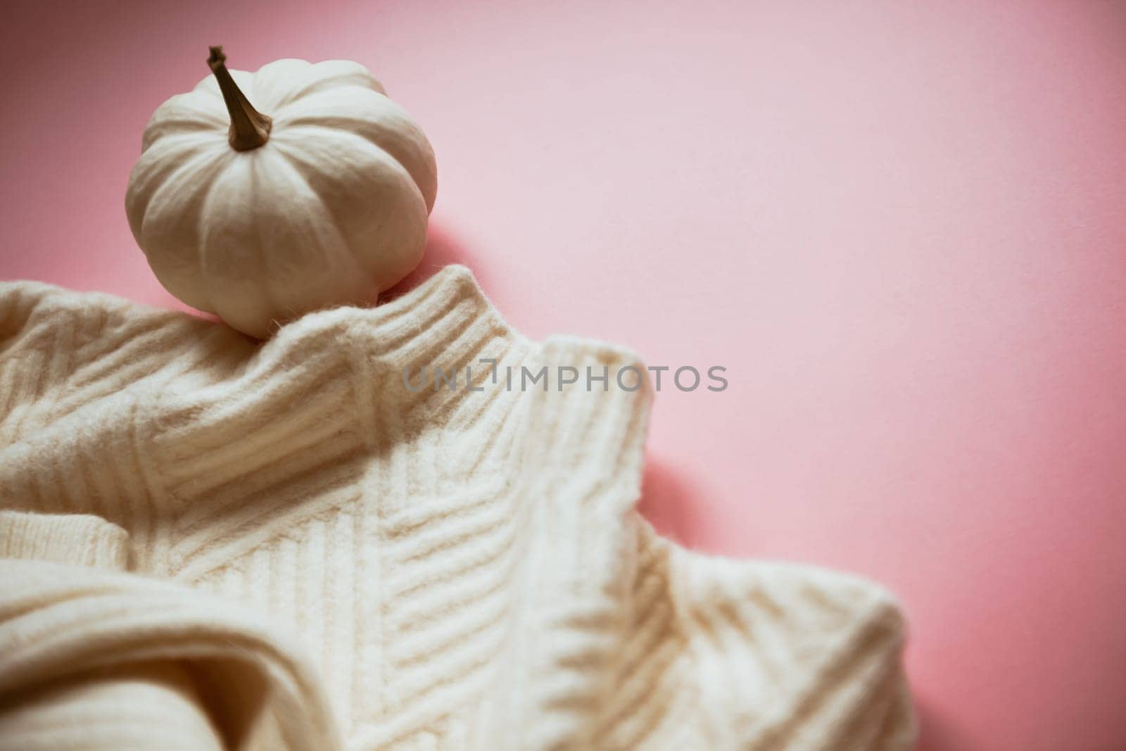 Creative autumn white sweater and pumpkin on millennial pink background copy space minimal style with natural light and shadows. Fall season template for feminine blog social media