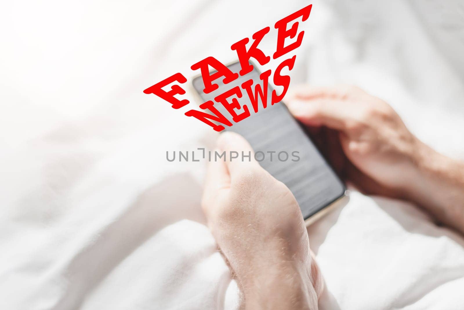 Fake news infodemics during Covid-19 pandemic concept. Man hands holding mobile phone reading global news or social net at home. Reading last news update in lockdown. Red text fake news on foreground
