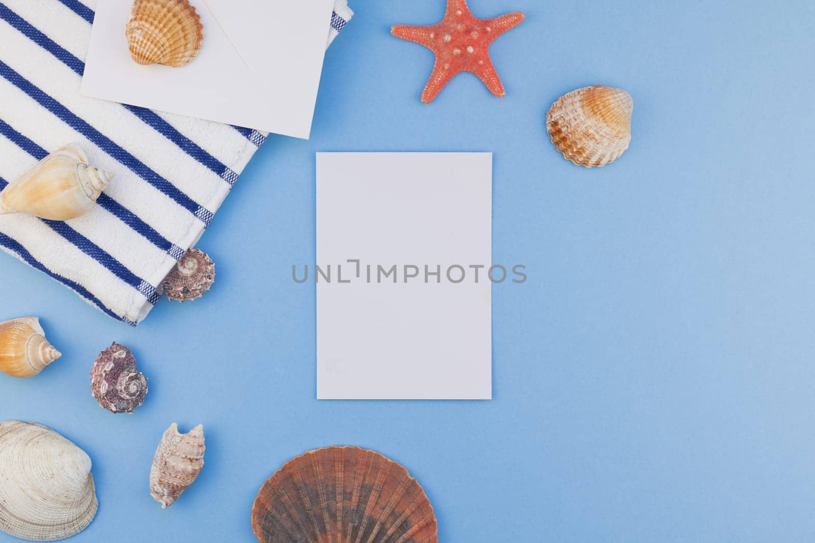 Creative flat lay concept of summer travel vacations. Top view of beach towel and seashells and starfish on pastel blue background with copy space in minimal style, template for text