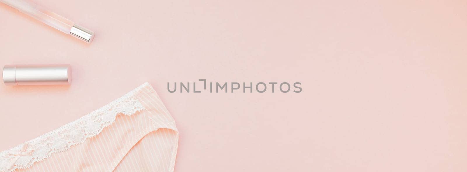 Feminine flat lay set of female panties and accessories, perfumes, lipstick on pastel pink color long wide banner for fashion blog and social media with copy space for text