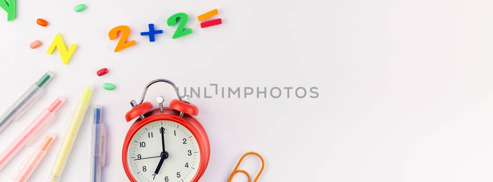 Long wide banner back to school concept with alarm clock, color school and office supplies on white table background with copy space, frame, template for text or design
