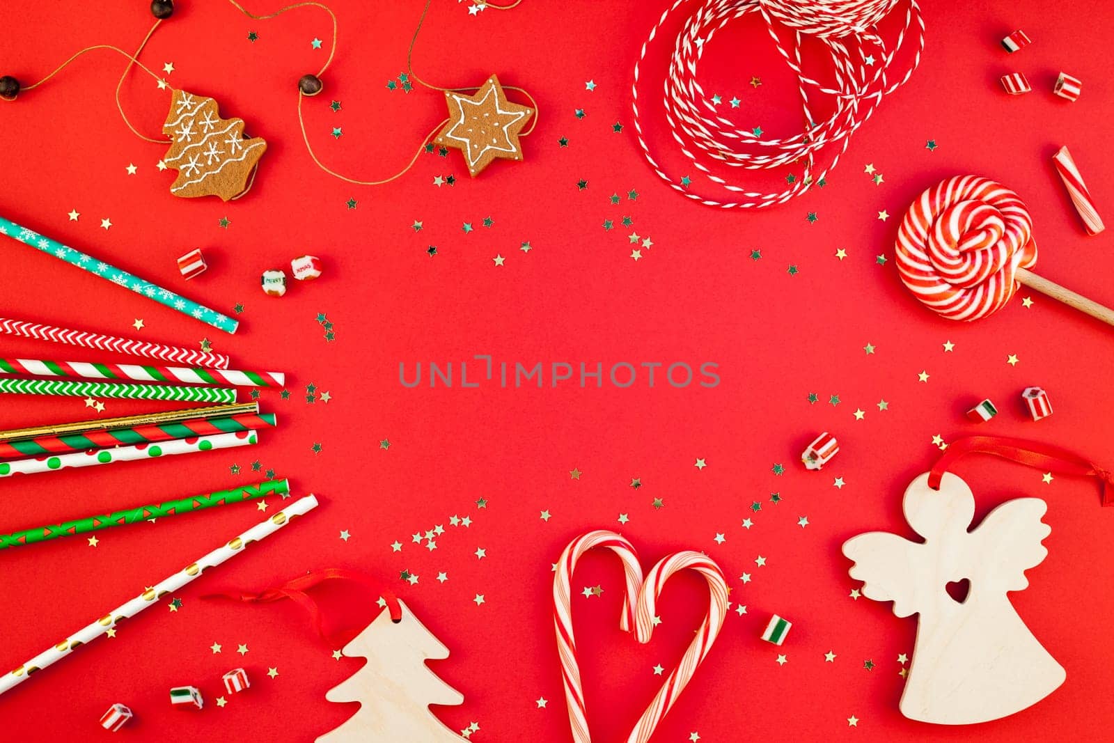 New Year or Christmas decoration flat lay top view Xmas holiday celebration handmade decor wooden toys sweets golden stars glitter on red paper background. Template frame for greeting card your design