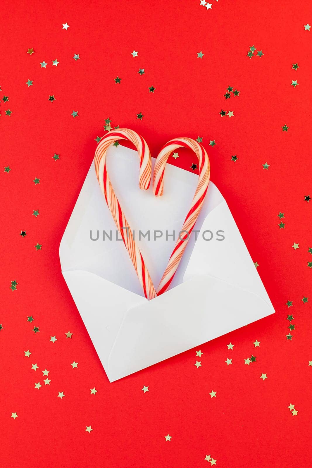 New Year or Christmas decoration flat lay top view Xmas holiday celebration handmade decor sweets golden stars glitter on red paper background. Template frame for greeting card your design