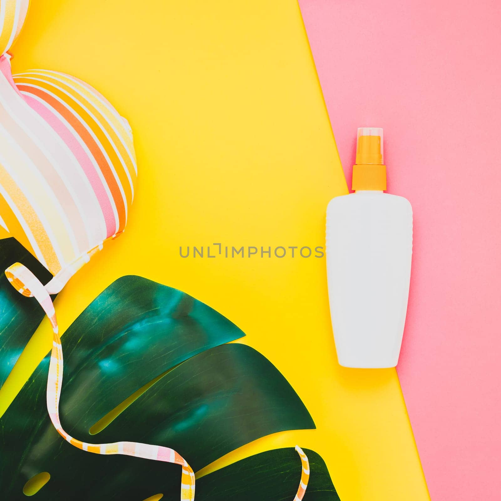 Tropical jungle palm monstera leaves, sunglasses, sunscreen blank bottle mockup and woman's swimsuit top on bright square color paper background. Summer vacations creative flat lay concept template