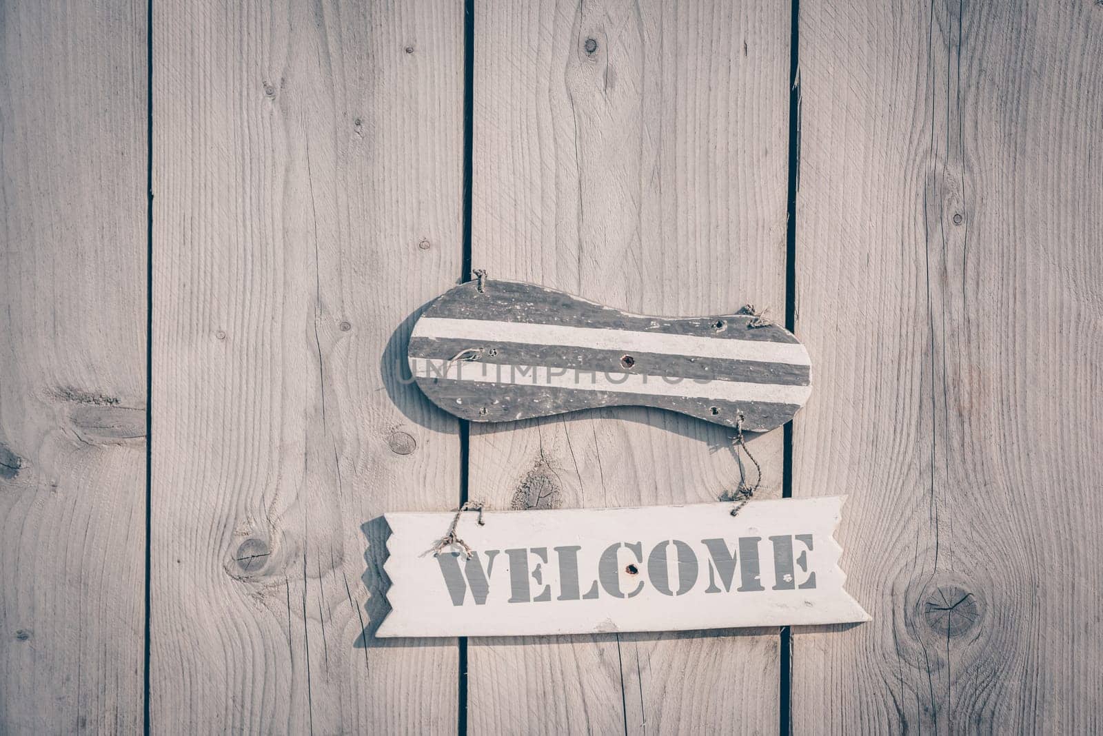Wooden welcome sign in rustic style hanging on plank door