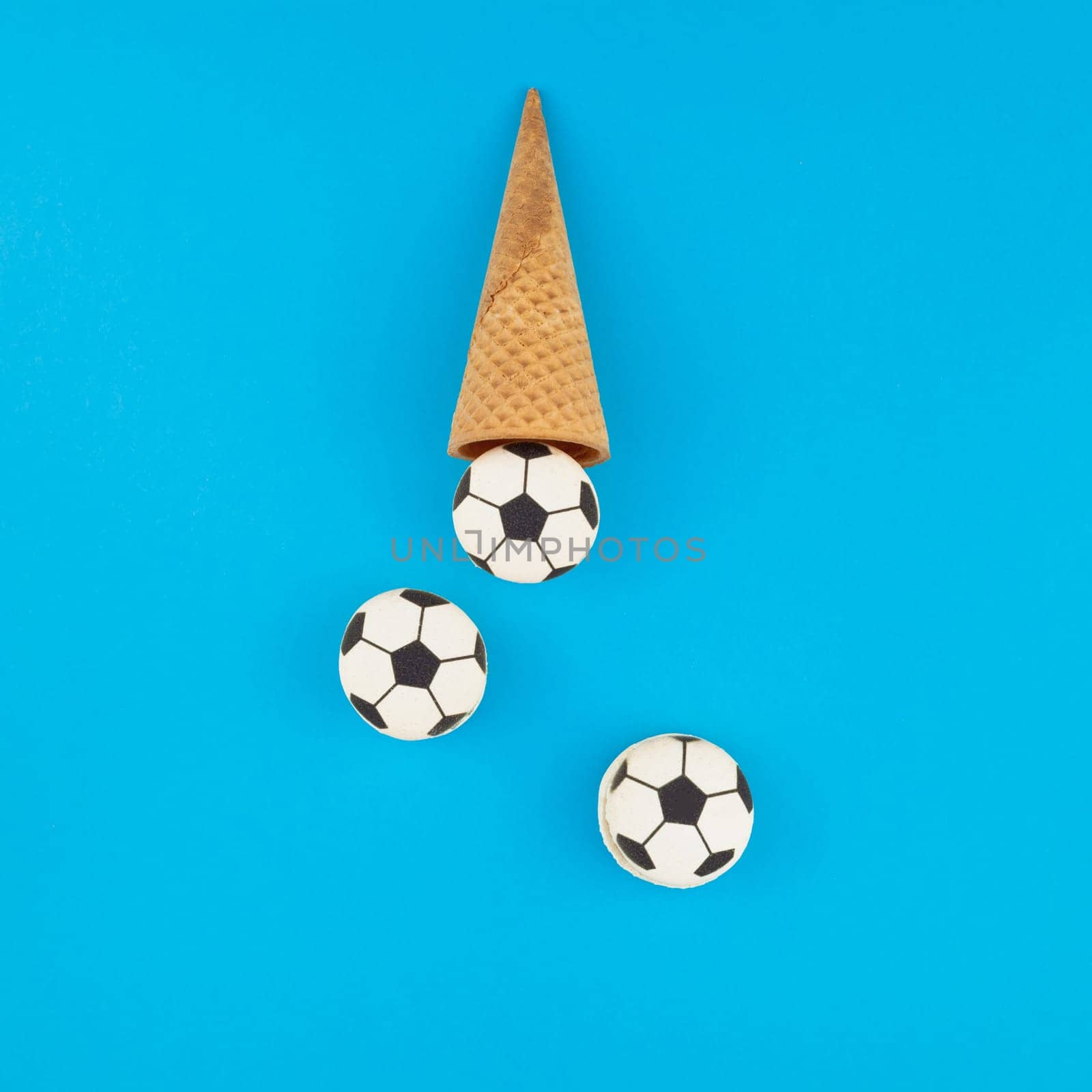Square Creative flat lay top view of ice cream waffle cones with soccer balls macarons on bright bold blue background with copy space in minimal style, concept of football games for children birthday