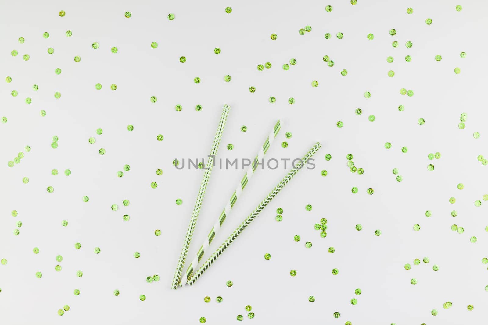 Holiday pattern flat lay top view Xmas Christmas New Year celebration drinking cocktail fun party straws green golden sparkles glitter white background. Template for greeting card your text design