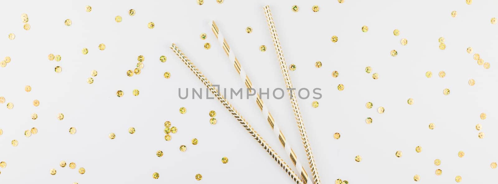Holiday pattern flat lay top view Xmas Christmas New Year celebration drinking cocktail fun party straws golden sparkles glitter white background. Template for greeting card long wide banner
