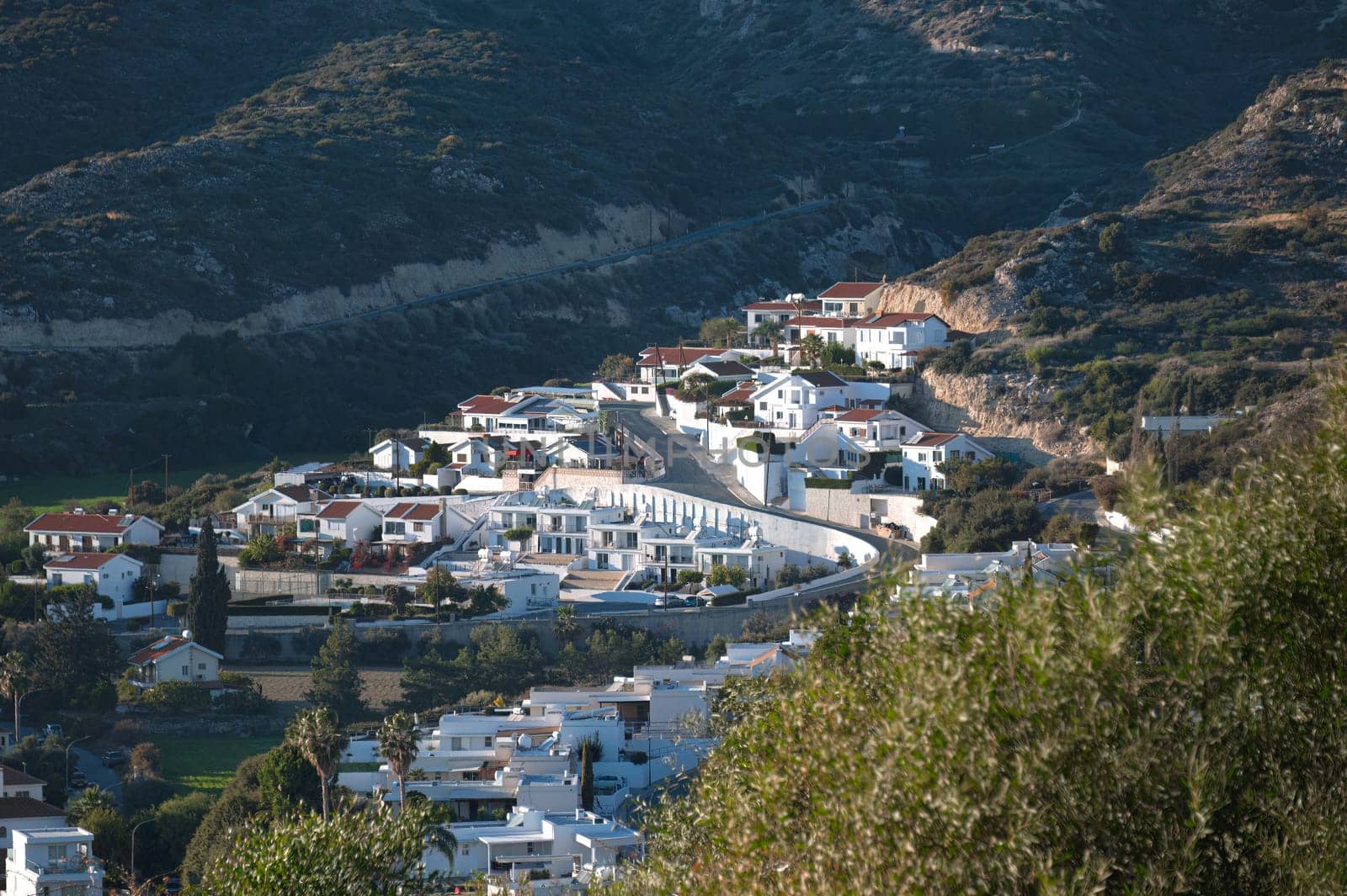 White houses with red tile roofs are overlooking a valley on a sunny day in Pissouri, Cyprus