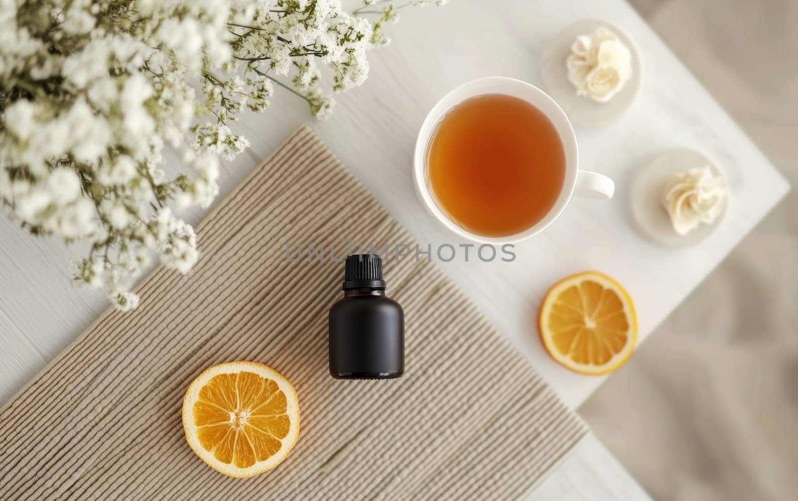 Calming tea scene with cup of herbal tea, essential oil bottle, lemon slices, and delicate white flowers on textured background, perfect for relaxation.