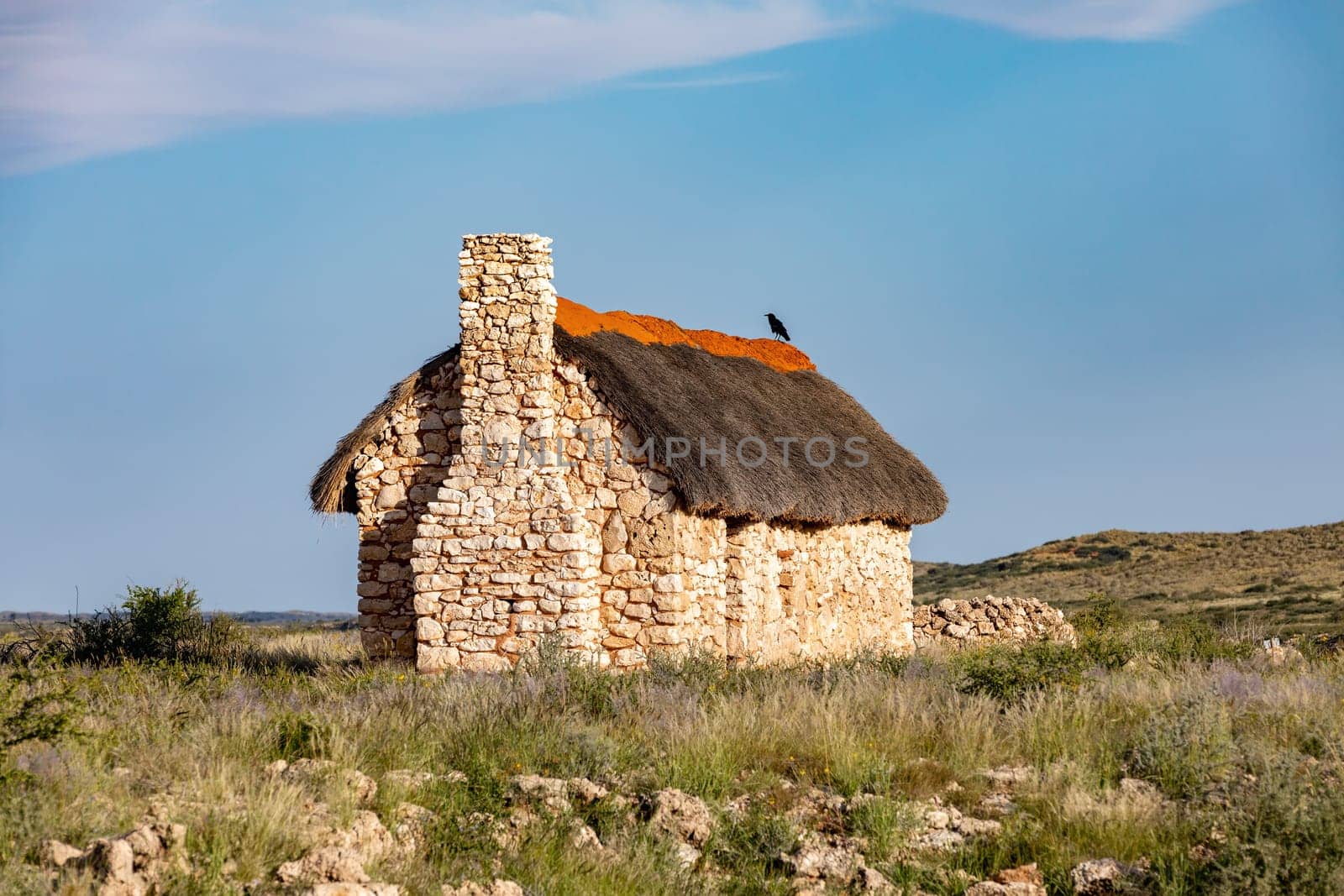 Alone stone house, weathered by the harsh elements, sits amidst the arid landscape of the Kalahari desert, South Africa