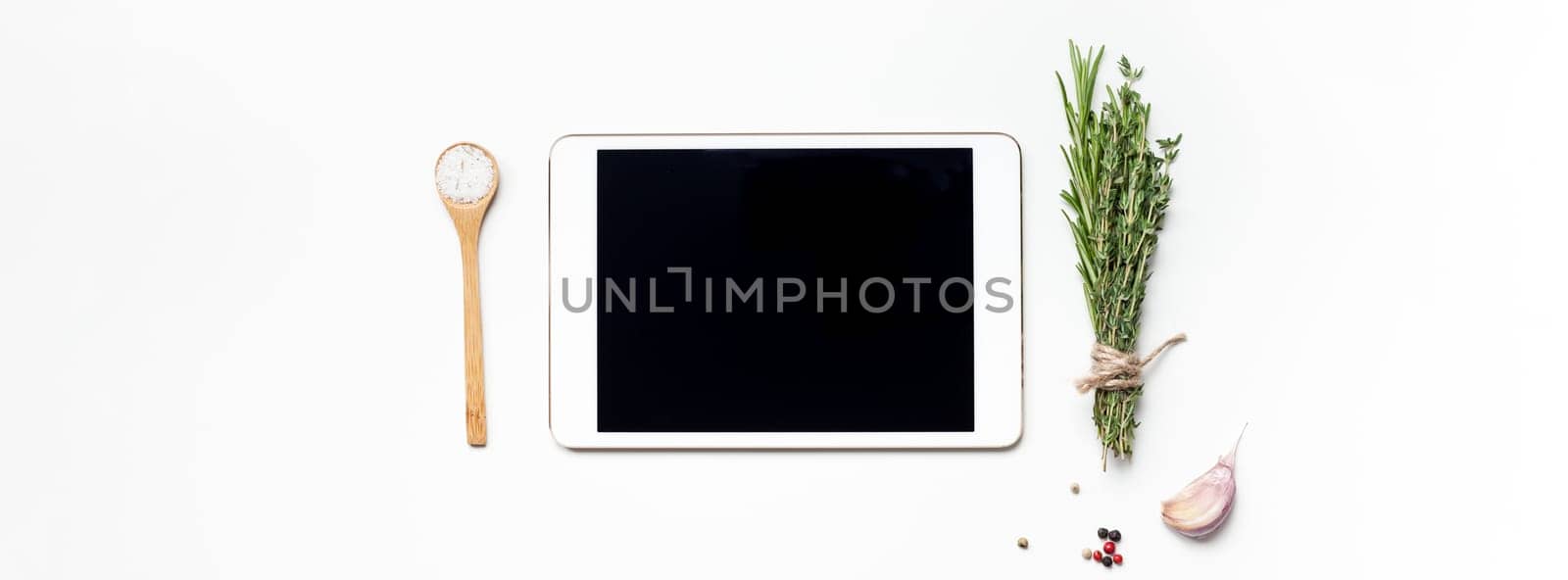 Flat lay overhead view tablet PC gadget mockup blank text space on white background with greens herbs and spices. Menu design food blog recipe cookbook or delivery app with cooking ingredients