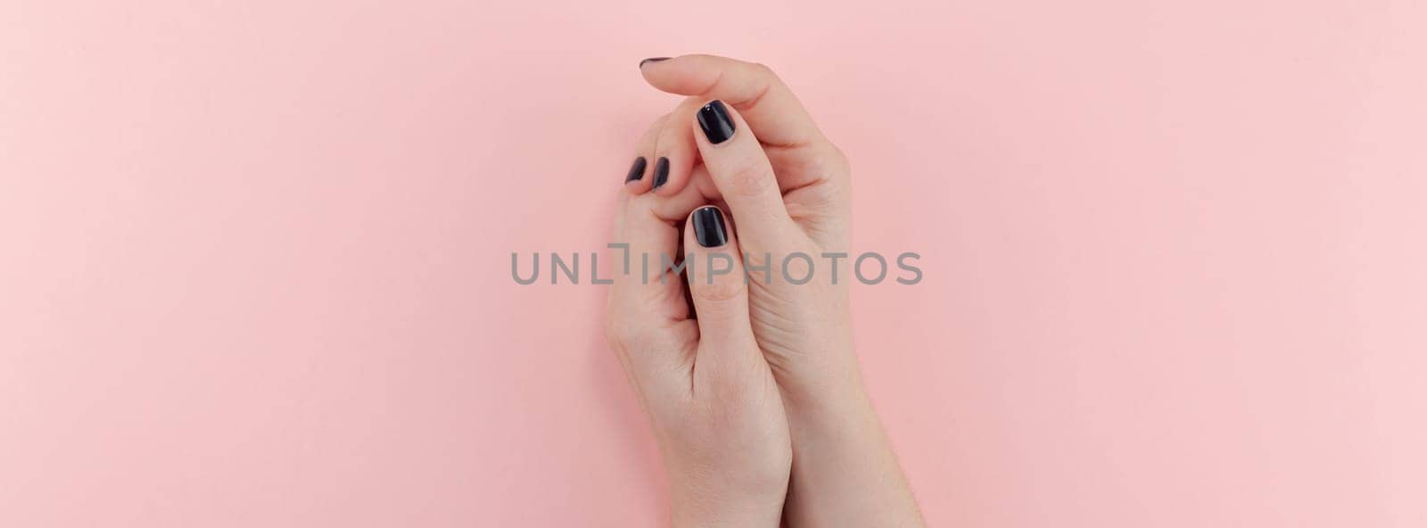 Stylish trendy female black manicure. Beautiful young woman's hands on millennial pink pastel background. Beauty and SPA concept. Banner Template for feminine blog social media