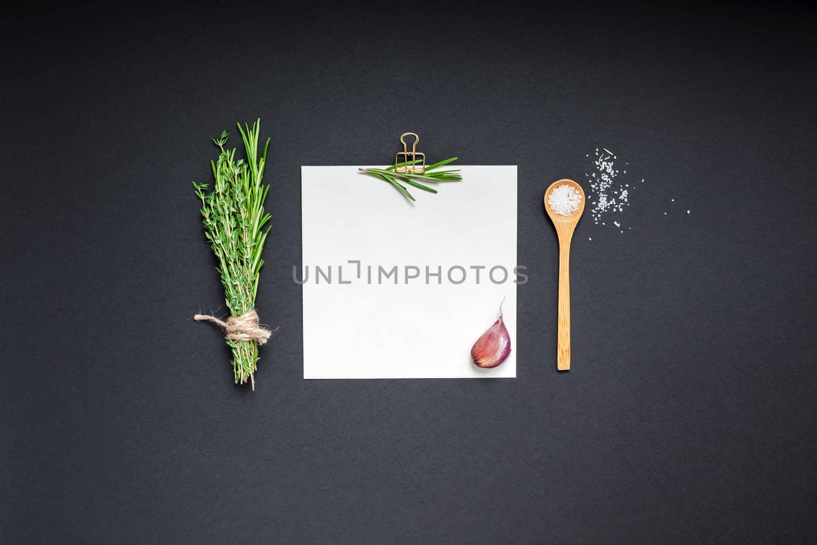 Flat lay overhead view blank recipe paper page with clip mockup text space invitation card on black background with greens herbs and spices. Menu recipe book food blog design with cooking ingredients