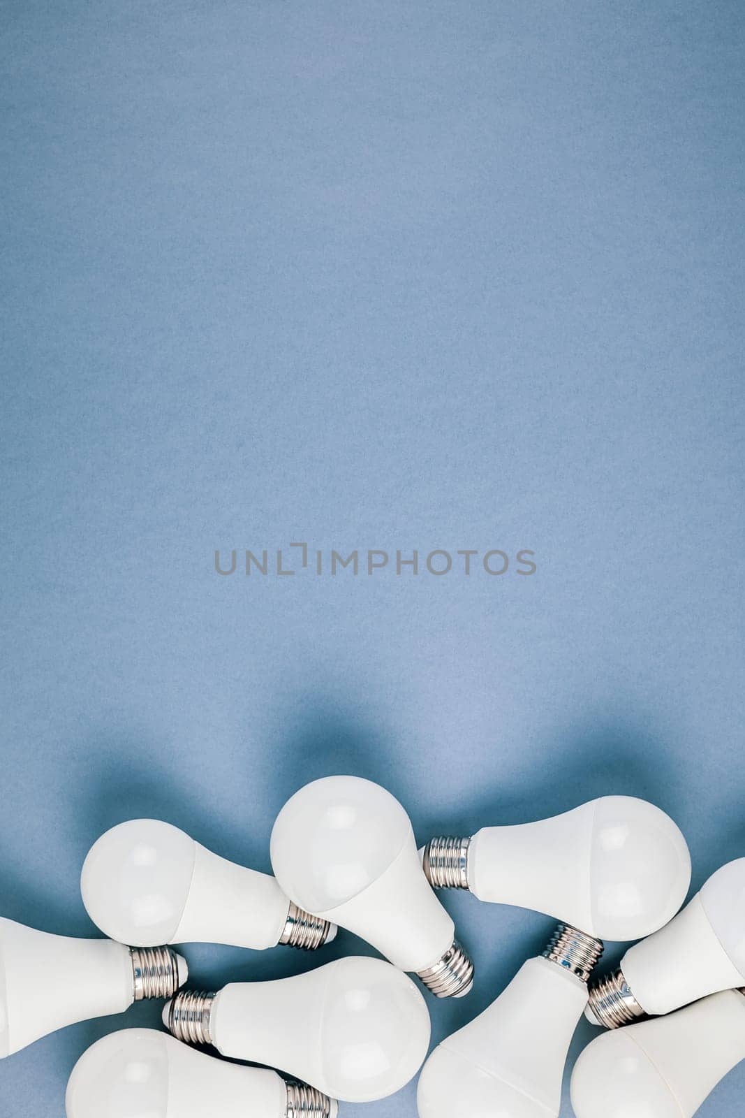 Energy-saving and eco-friendly life in conceptual frame pattern. Creative top view flat lay of LED light bulbs composition with copy space on blue background in minimal style.