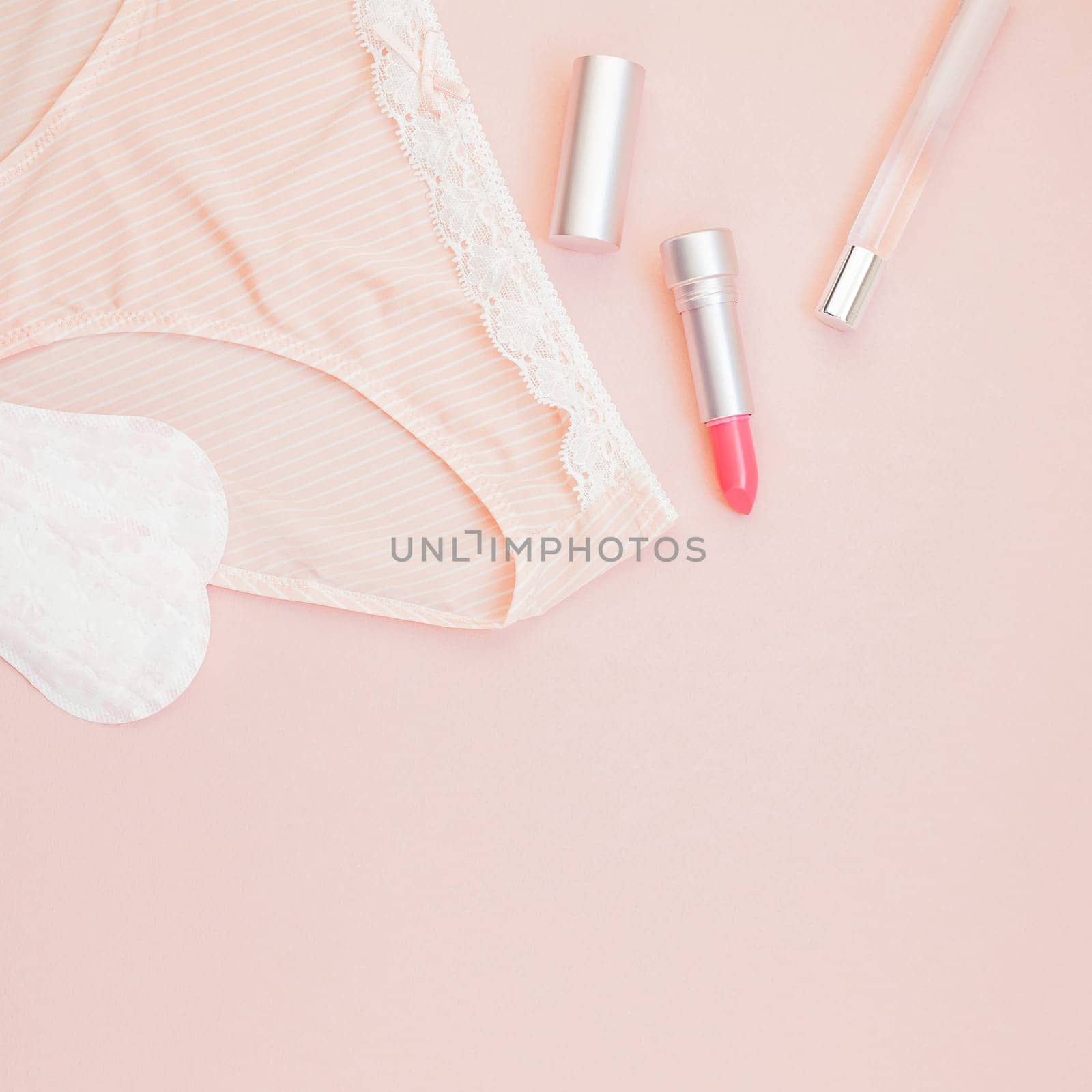 Square Feminine flat lay set of female panties and accessories, perfumes, lipstick and pads liners on pastel pink color background for fashion blog and social media with copy space for text