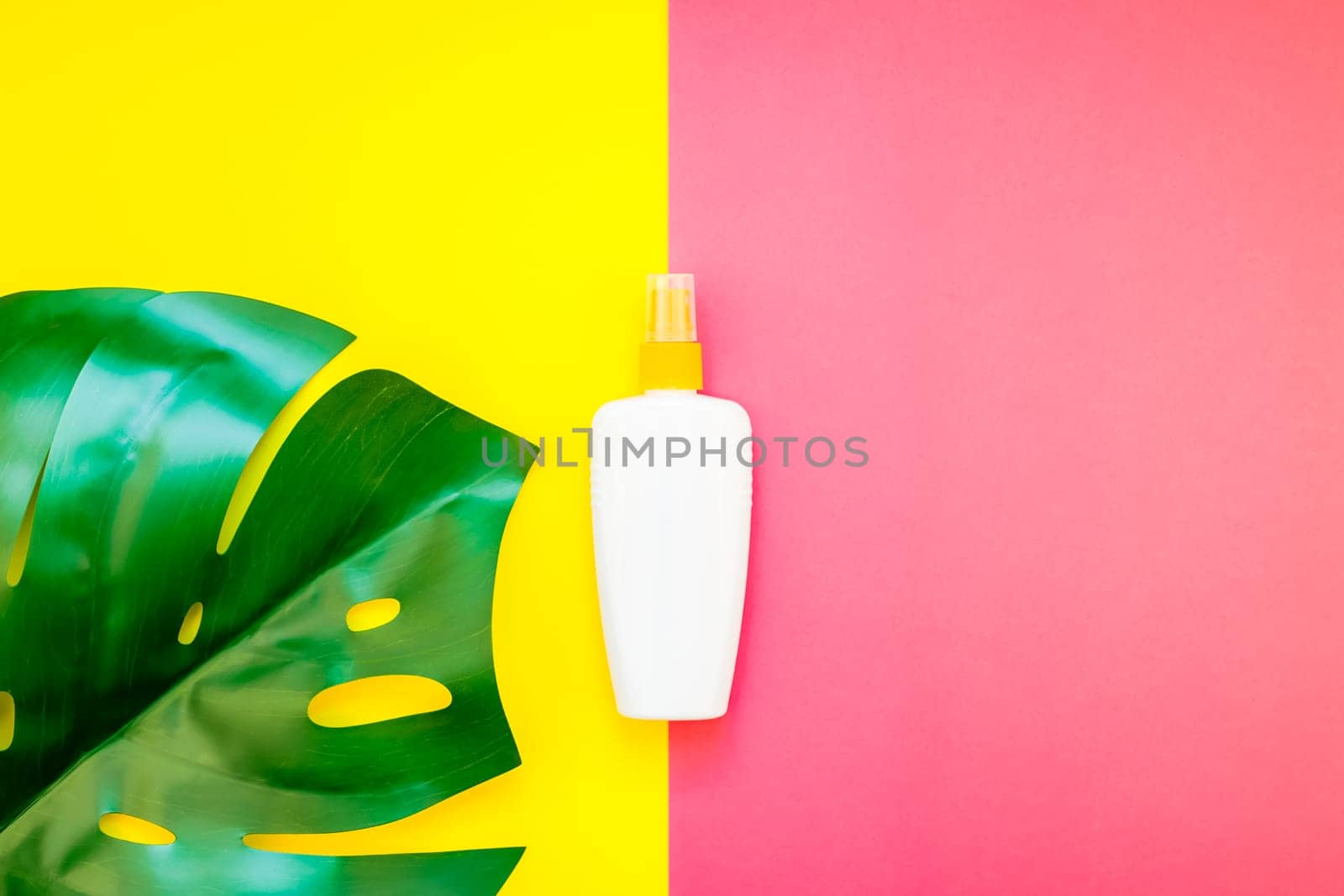 Tropical jungle palm monstera leaves and sunscreen blank bottle mockup on bright yellow and pink duotone paper background. Summer vacations creative flat lay concept template for text