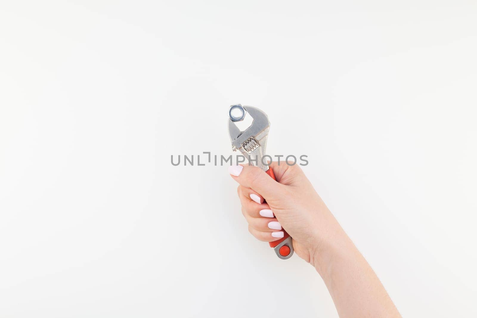 Creative image of woman hand with pastel manicure polish holding spanner with copy space isolated on white background in minimalism style. Repair or improvement feminism concept
