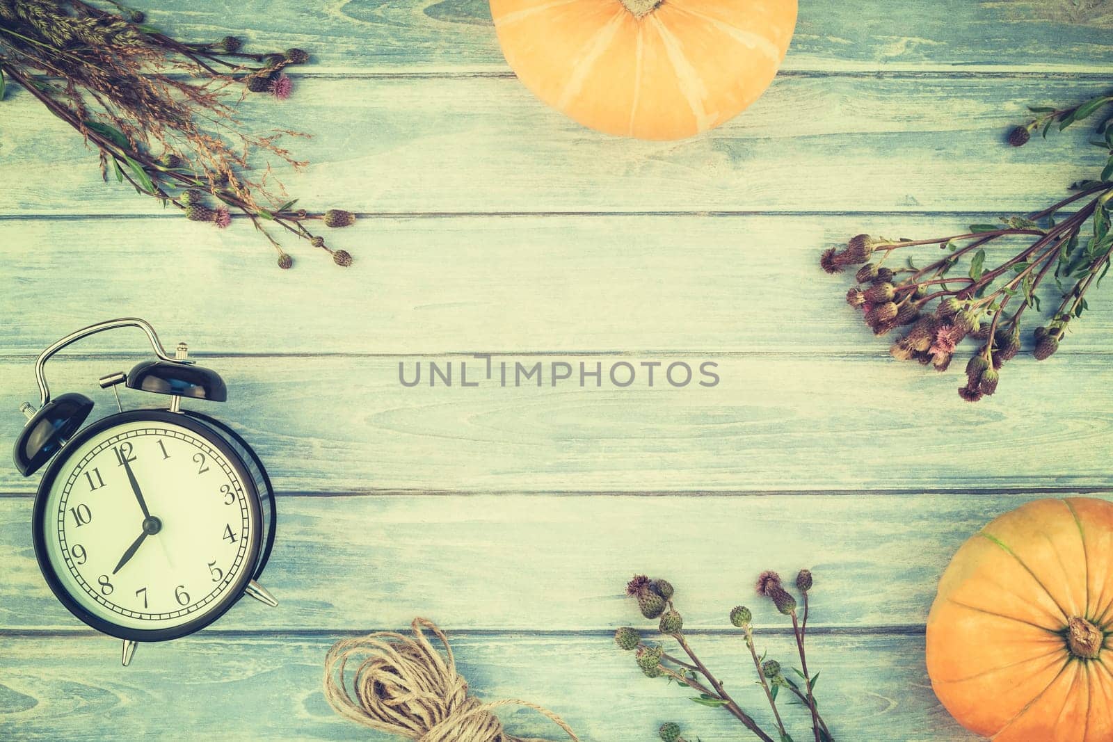 Top view of autumn orange pumpkins and dry flowers and grass in box thanksgiving background over blue toned wooden table with copy space. Template for fall harvest mood text