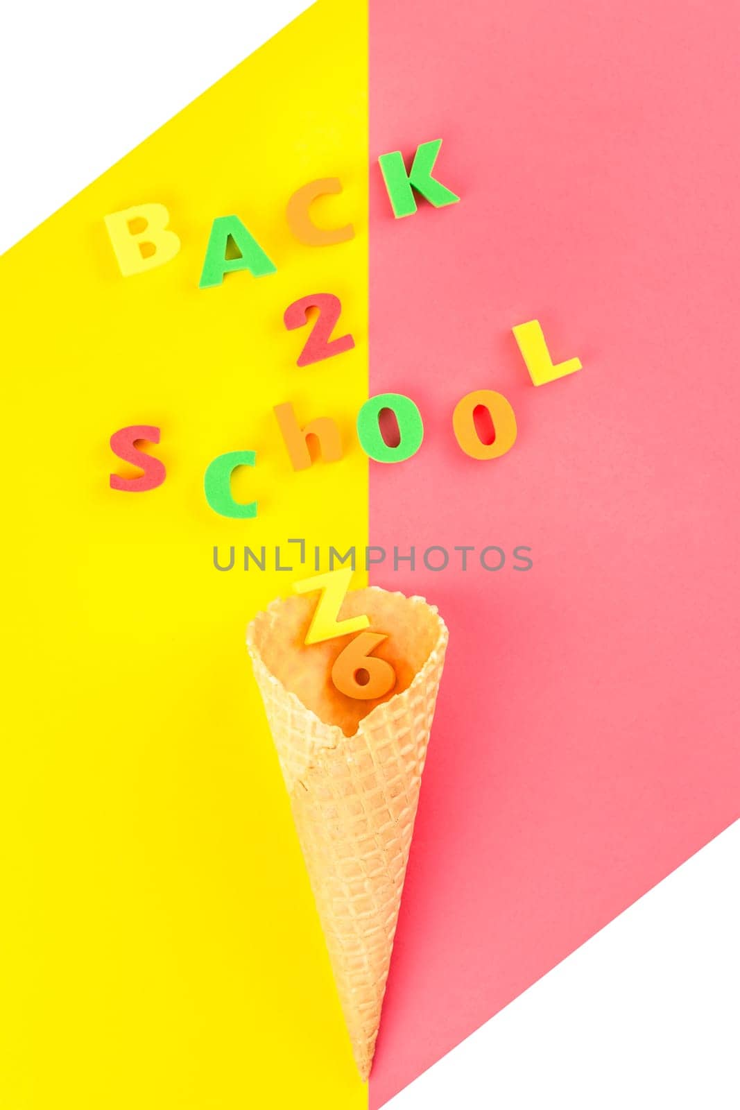 Creative flat lay back to school concept with waffle cone and welcome letters message on bright yellow and pink paper background with copy space, template for text or design