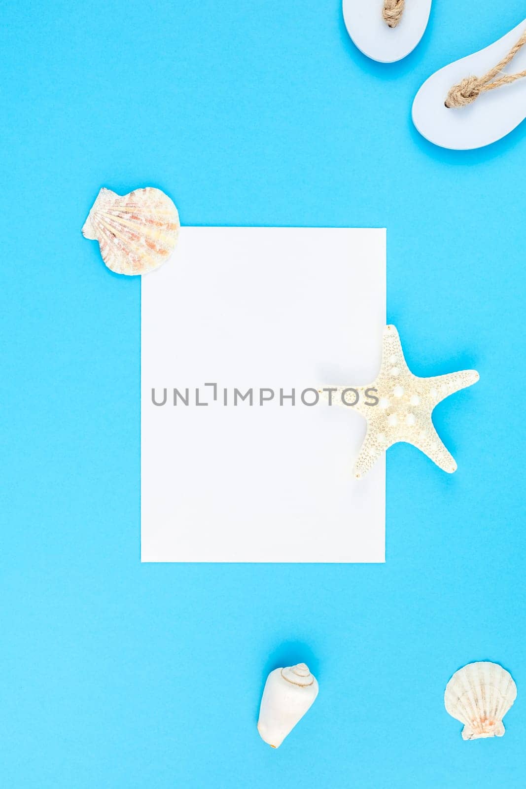 Creative flat lay concept of summer travel vacations. Top view of seashells and starfish on turquoise blue background with postcard mock up and copy space in minimal style, template for text