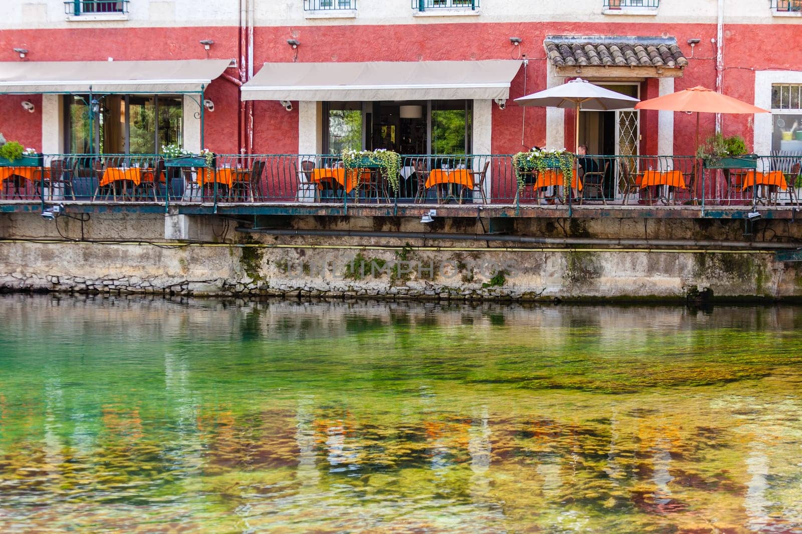 Small cafe with wicker furniture and umbrellas on a quay in a french town