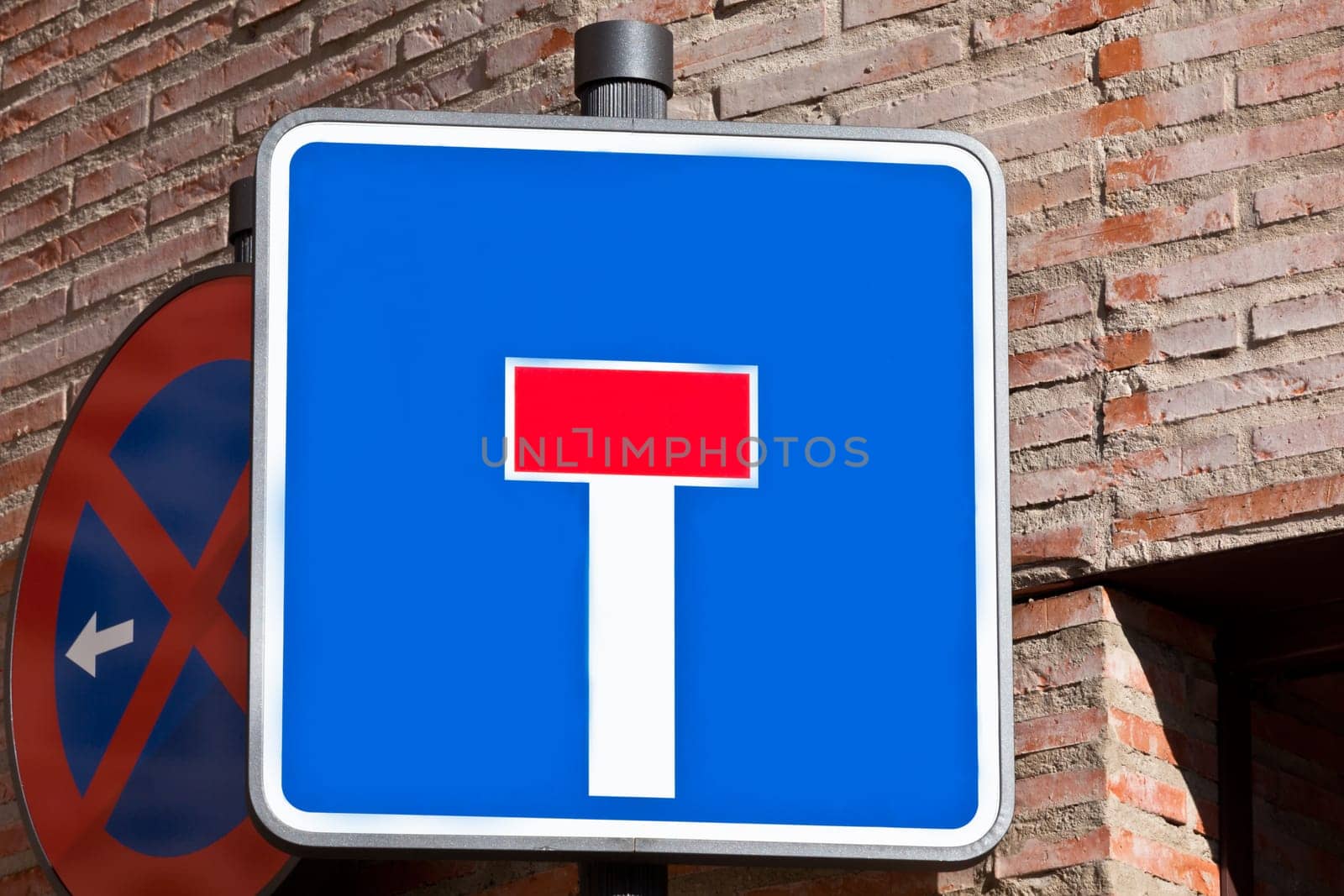 "Dead end"" and ""Don't stop"" road signs on the bick house wall"