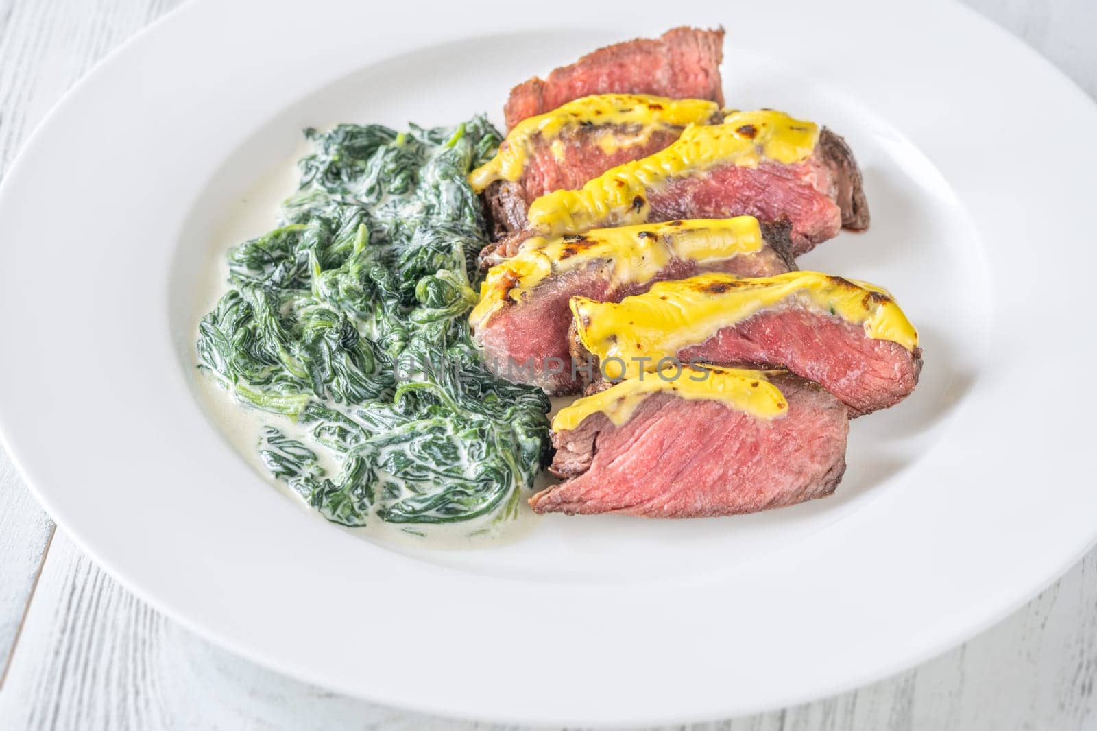 Cheese topped beef steak with creamy spinach