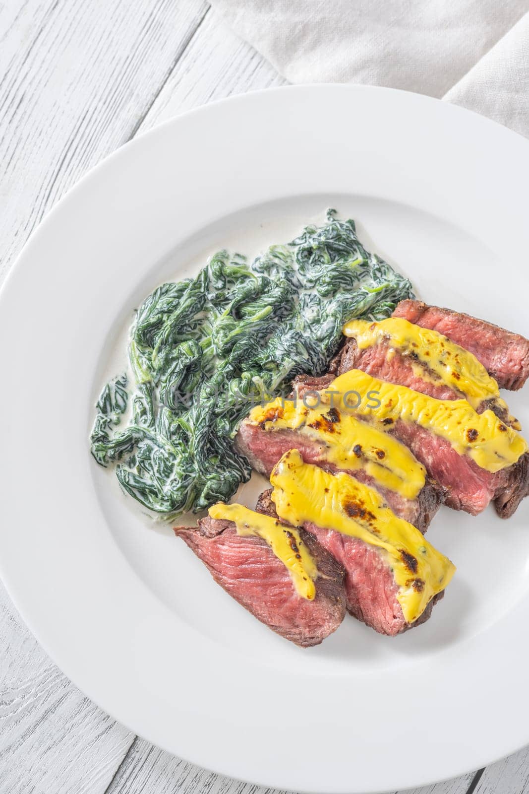 Cheese topped beef steak with creamy spinach