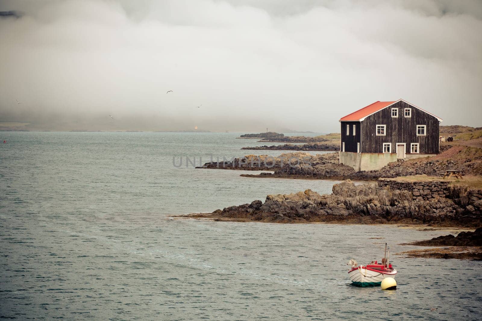 Lonely Black Wooden House and boat at coastlineÊin East Iceland. Horizontal toned shot