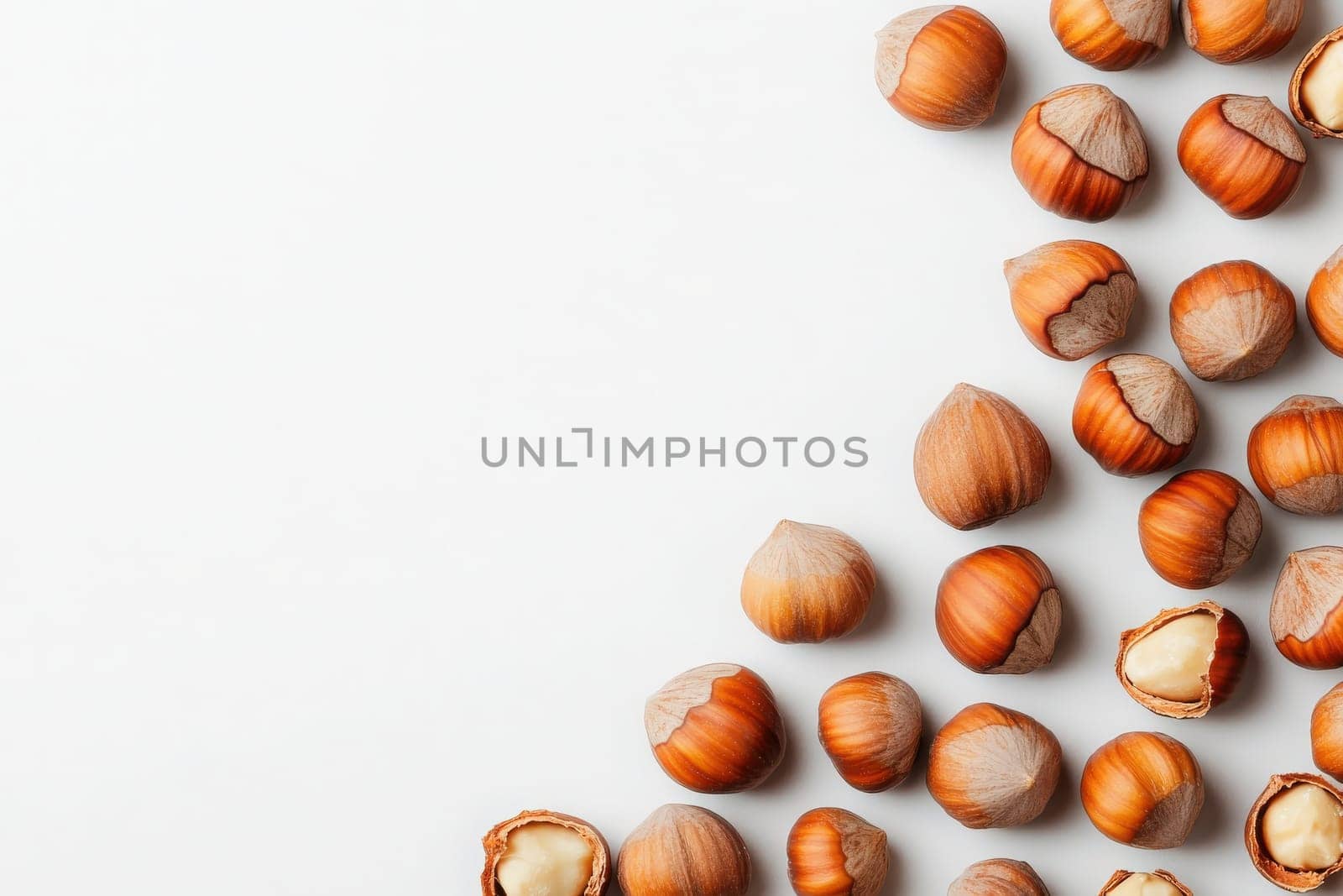A collection of whole hazelnuts, both shelled and unshelled, is artfully scattered in the center of a white background. These nuts are perfect for baking, snacking, or garnishing dishes.